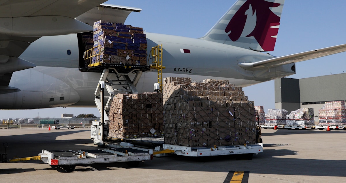 Air-freight pallets being transferred beside a cargo aircraft